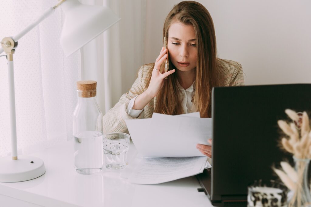 woman works with business papers and talks on the phone