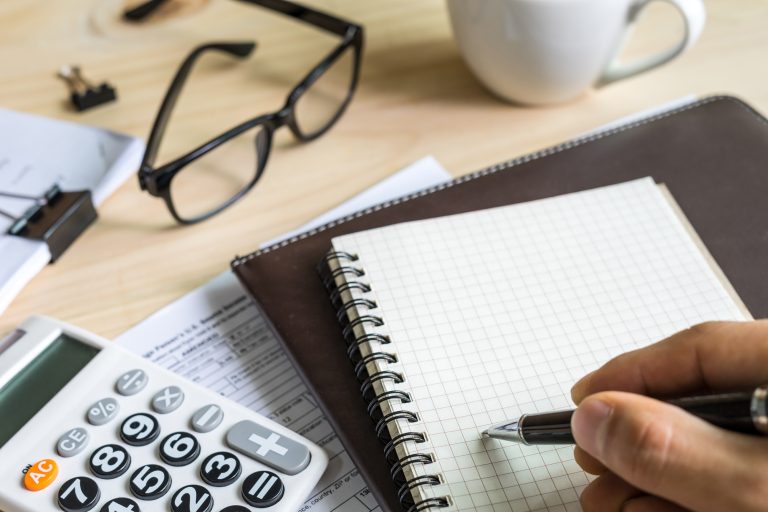 young man hand using calculator and writing
